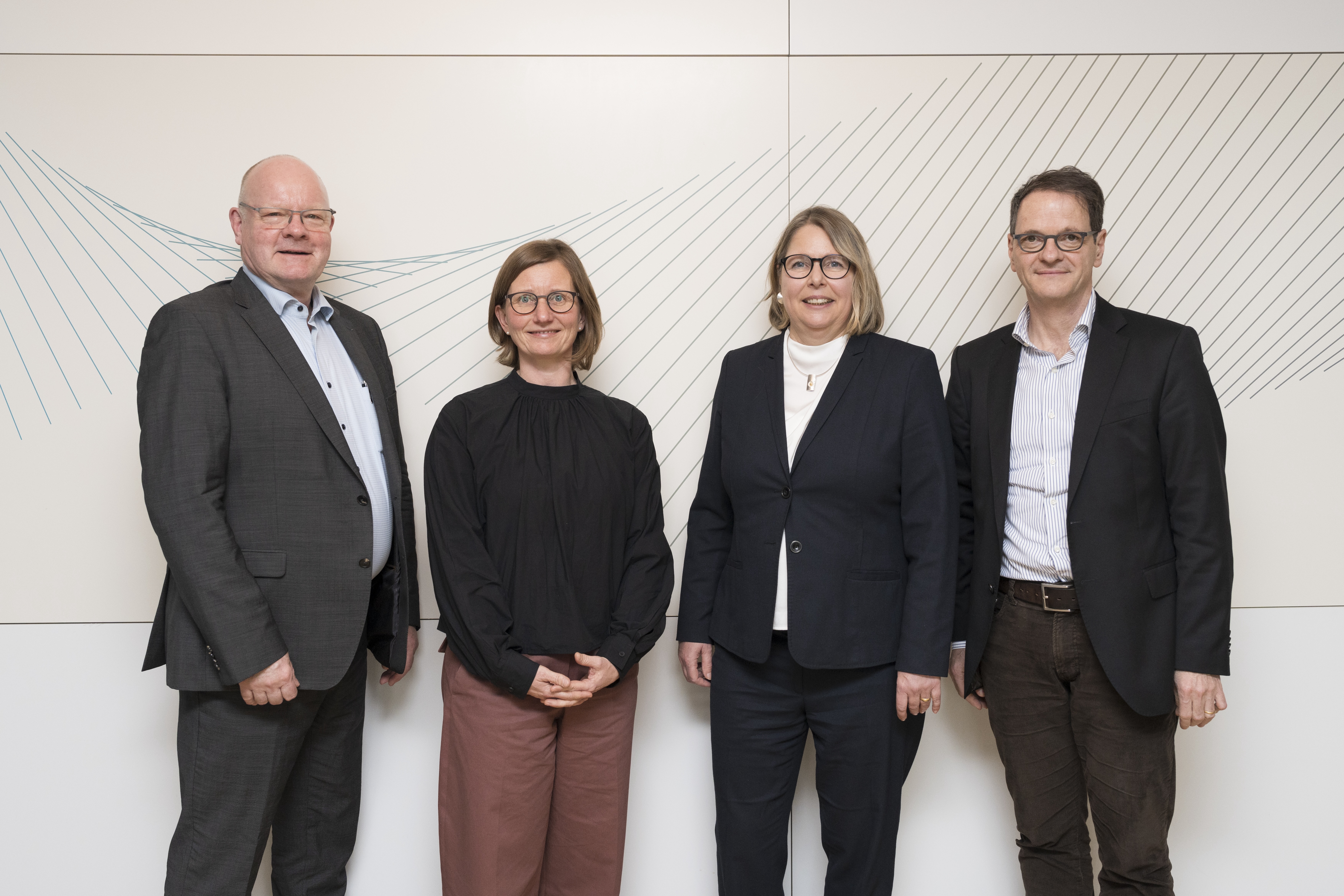 Gruppenbild mit vier Personen. Zwei Frauen stehen in der Mitte, flankiert von zwei Männern.